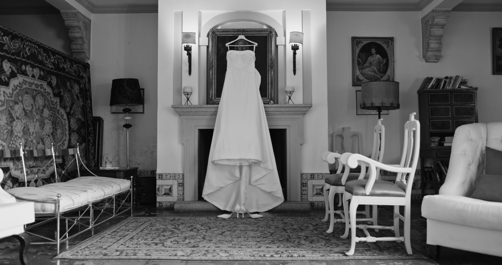 Vestido de novia colgado en una habitación clásica con espejos.