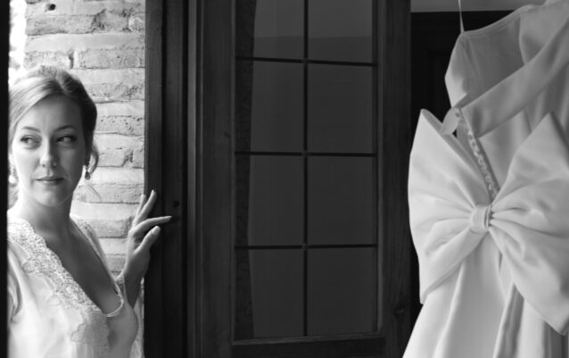 Novia sosteniendo el pomo de una puerta oscura, lista para salir.