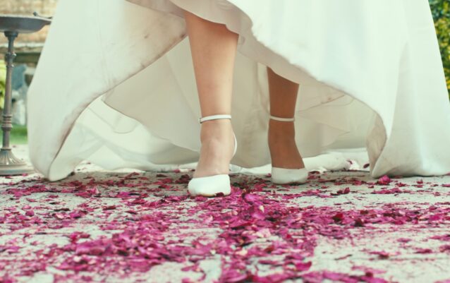 Pies de la novia caminando sobre pétalos de rosa.